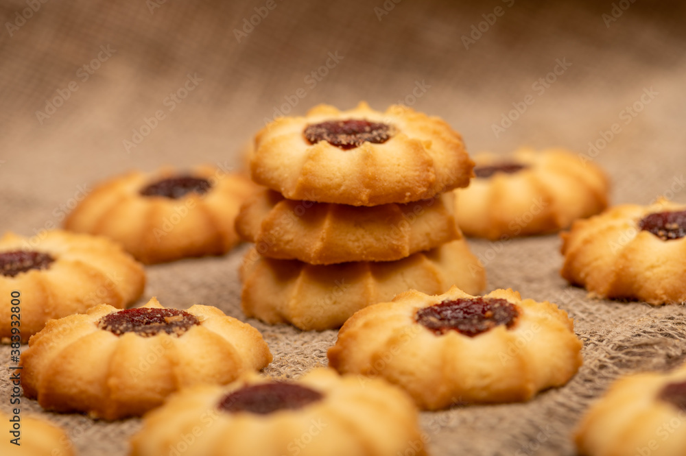 Homemade pastry cookies with jam on a background of homespun fabric with a rough texture, close-up, selective focus.