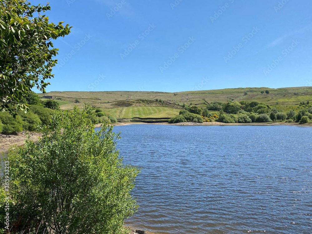 Leeming Reservoir, with trees, blue water, and fields in the distance, on a hot day near, Denholme Road, Denholme Leeming Reservoir, with trees, blue water, and fields in the distance, on a hot day near, Denholme Road, Denholme