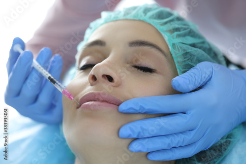 Portrait of woman whose lips are injected by beautician. Hyaluronic acid injections into lips concept