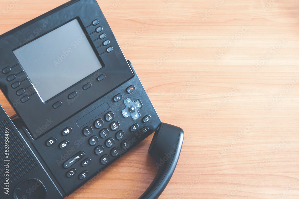 The black desktop push-button telephone. IP phone on desk in office. The black desktop push-button telephone. IP phone on desk in office.