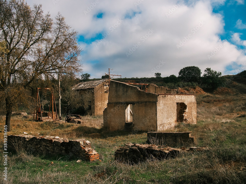 Abandoned house in ruins in the Andalusian countryside, surrounded by bushes and green area