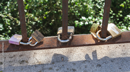 Keyless padlocks as a symbol of union in a couple anchored to the rail of a river.