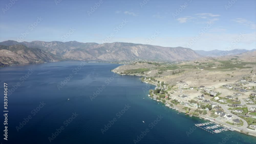Drone flying over houses towards lake and mountains. 4k Lake Chelan aerial footage. Scenic mountains around lake. Beautiful lake drone footage. Drone flying over houses towards lake and mountains. 4k Lake Chelan aerial footage. Scenic mountains around lake. Beautiful lake drone footage.