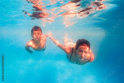 Mother and son diving on a swimming pool
