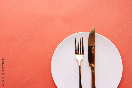 white plate, fork, knife on red table, elegant tableware 
