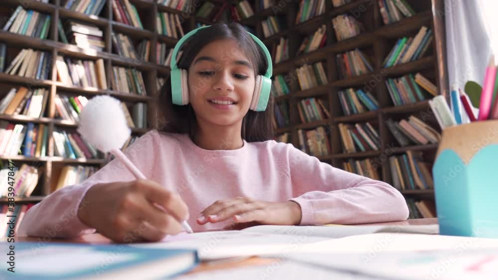 Cute indian latin preteen girl school kid child pupil wearing headphones raising hand distance learning online talking to camera at virtual lesson class by video conference call at home, webcam view. Видео Stock | Adobe Stock