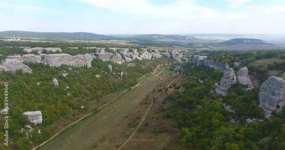 Drone shot flying close to a huge rock cliff. Aerial view on Crimea landscape with cliffs and mountains. Steep cliff face and mountain line. Large cliff surrounded by forest. 4 k video Drone shot flying close to a huge rock cliff. Aerial view on Crimea landscape with cliffs and mountains. Steep cliff face and mountain line. Large cliff surrounded by forest. 4 k video