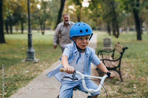 grandfather teaching his grandson to ride a bike in park