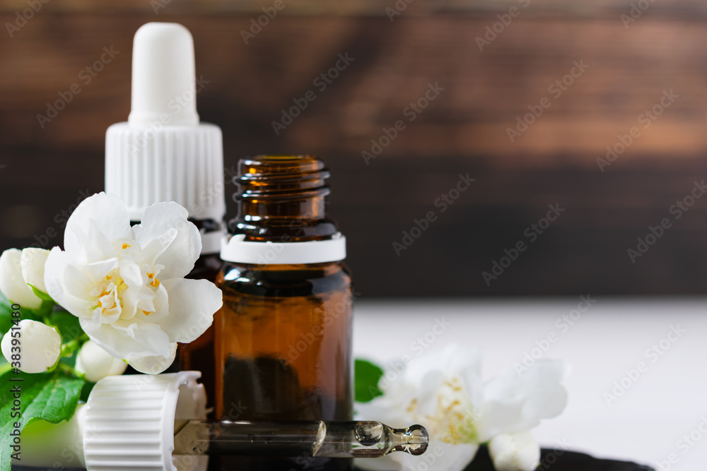 natural cosmetic product, jasmine oil with glass bottles on a wooden table natural cosmetic product, jasmine oil with glass bottles on a wooden table