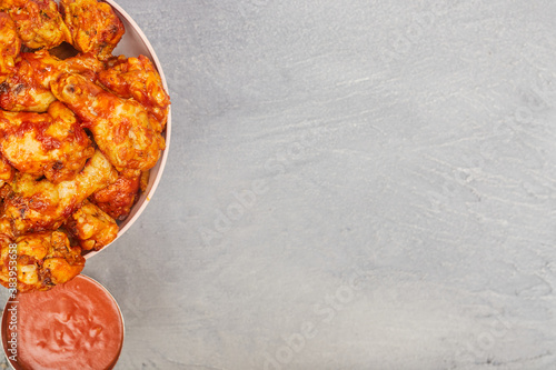 Buffalo chicken wings in a plate on a gray concrete background, copy space