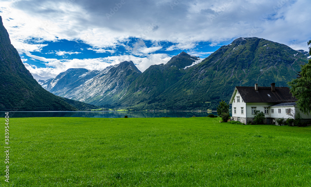 Urlaub in Süd-Norwegen: der schöne klare Berg-See Oppstrynsvatnet mit Haus und saftiger Wiese / Segestad