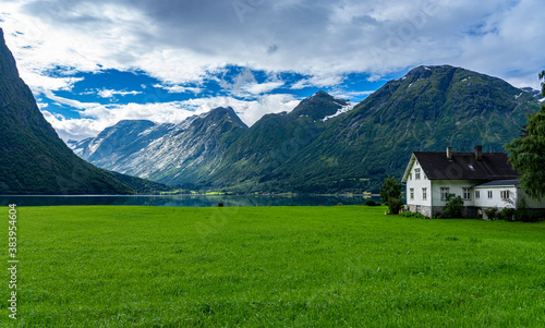 Urlaub in Süd-Norwegen: der schöne klare Berg-See Oppstrynsvatnet mit Haus und saftiger Wiese / Segestad