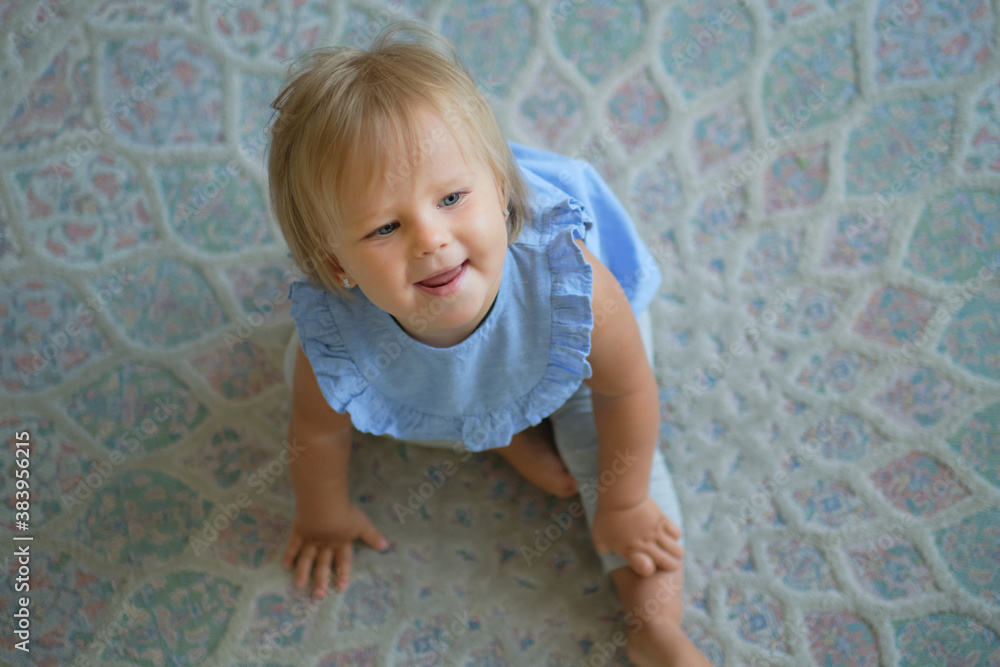 Fototapeta premium childhood, babyhood and people concept. happy little baby girl sitting on floor at home. view from above