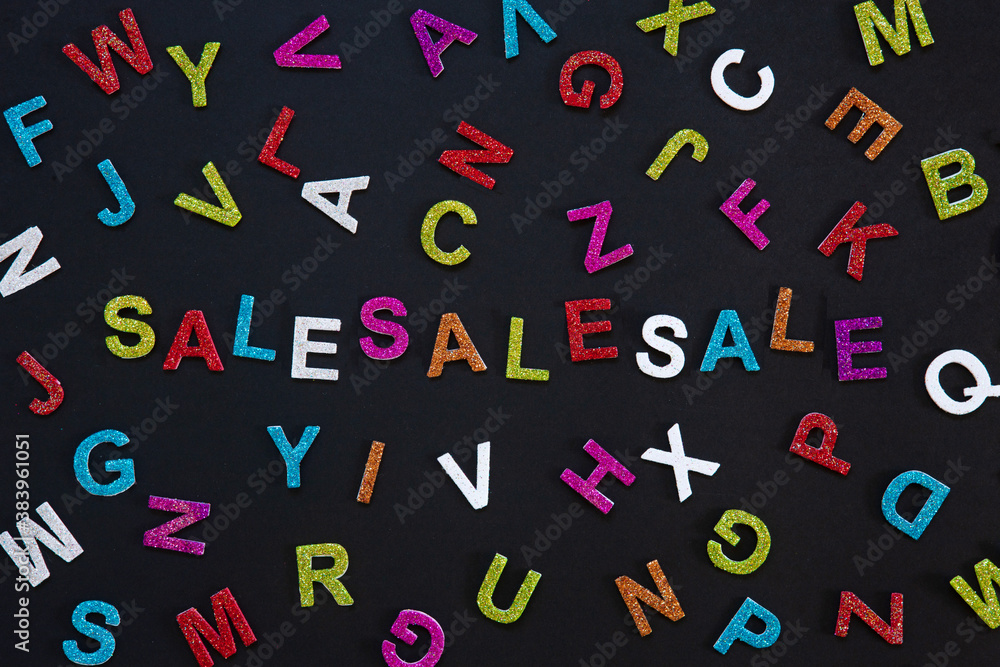 Sale label on a black background surrounded by colorful letters of the alphabet