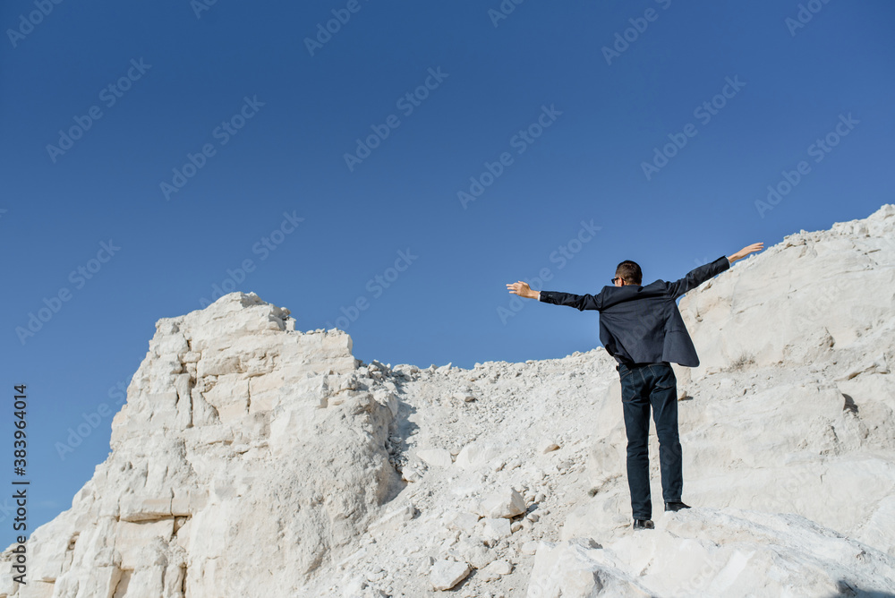 Back view of young man businessman that are standing on the top of the mountain Back view of young man businessman that are standing on the top of the mountain