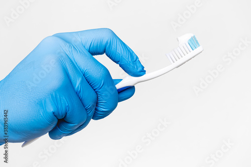 Doctor's hand in a blue medical glove holds a toothbrush Isolated on a white. dentistry. toothpaste on a toothbrush. oral hygiene. healthy teeth