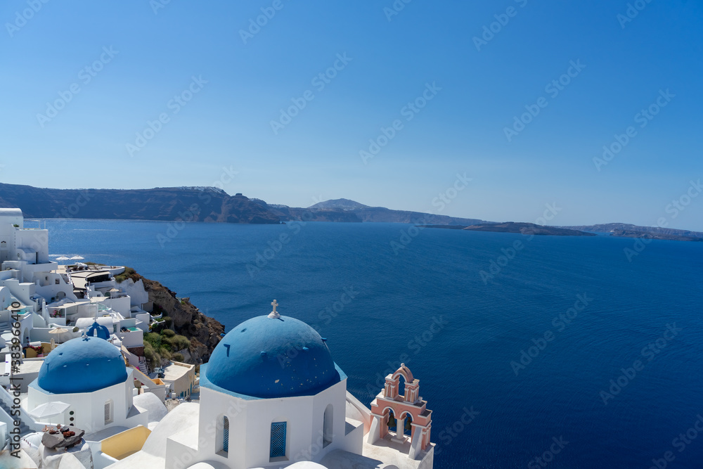 Iconic view of Santorini, with typical blue dome church, sea and white facades. Detail of the roof of an orthodox church.  Blue domed church along caldera edge in Oia, Santorini