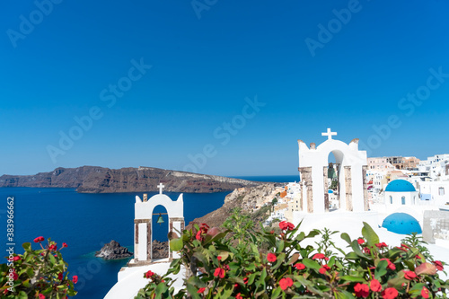 View of Santorini caldera with Oia town and famous old white tower bells and blue domes of orthodox churches