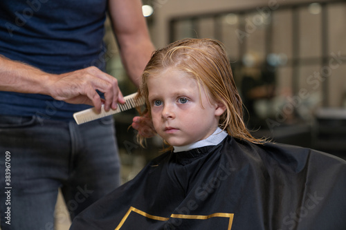 blond boy in a beauty studio getting a haircut and styling