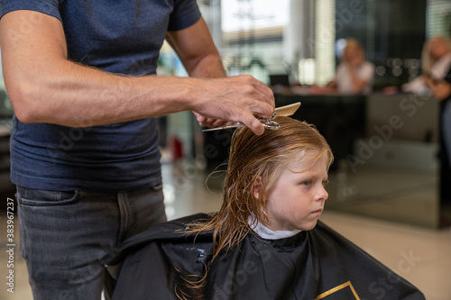 blond boy in a beauty studio getting a haircut and styling