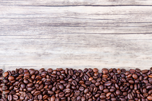 Coffee beans on wooden background. Pile of coffee. Coffee beans on a wooden background. Top view. Copy space.