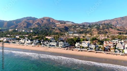 4K Aerial drone shot of Malibu Beach coastline in California with the blue Pacific Ocean with waves coming in and beach with nice houses on the background