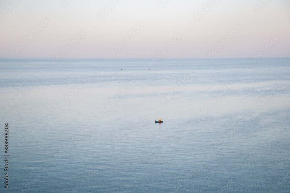 Beautiful seascape at sunset. View of a fisherman in a yellow boat at sea.