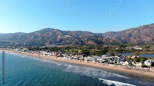 4K Aerial drone shot of Malibu Beach coastline in California with the blue Pacific Ocean with waves coming in and beach with nice houses on the background