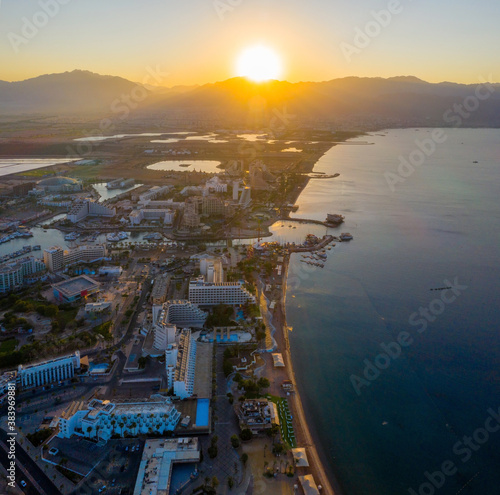 Fotografie Sunrise over Eilat and The Red Sea, with waterfront hotels and Edom mountain ridge in the horizon, Aerial view