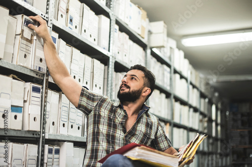 Man works in archive and reviews the different files photo