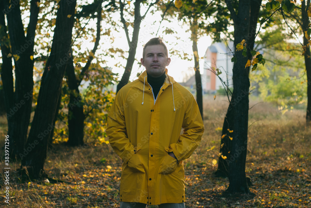 a man in a yellow raincoat in an autumn Park,