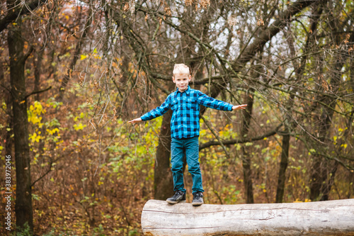 Preteen boy balance on fallen tree trunk © o_lypa