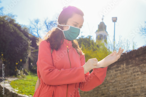 Young woman wearing protective mask on face and medical gloves.Beautiful stylish girl wear medical face mask on sunny city street.Coronavirus COVID-19 protection