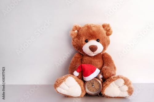 Teddy bear and alarm clock on silver background