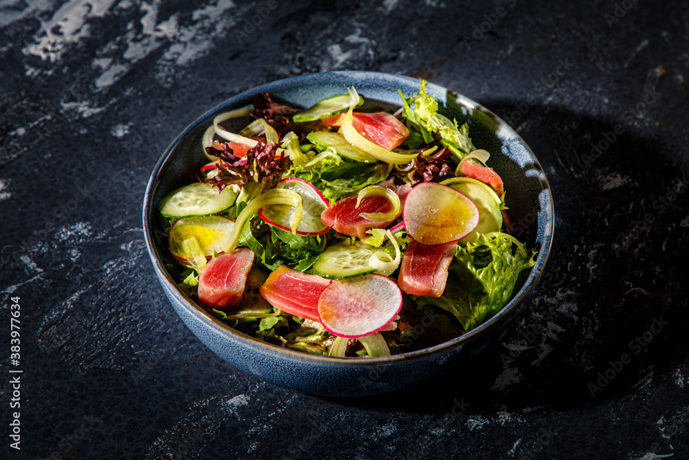 Salad of lettuce, tuna, cucumbers and radishes is on the plate