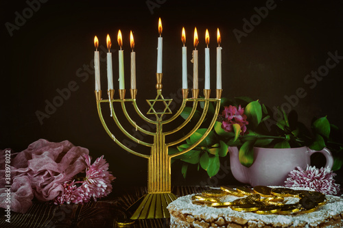 Jewish menorah with candles and holiday cake decorated with flowers. photo