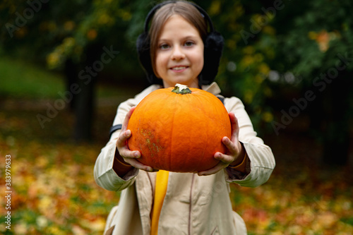 A little cute girl in an orange T-shirt makes an autumn application on paper, she glues autumn leaves, a child in the park on a mat, an autumn composition.