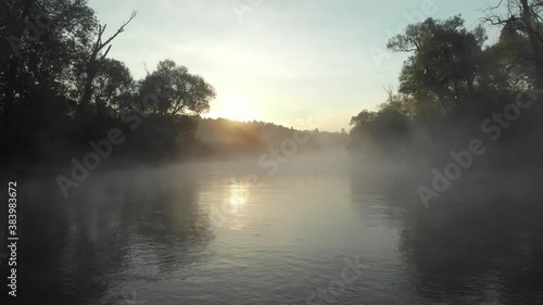 Flight on the drone over the river covered with mist in the early morning
