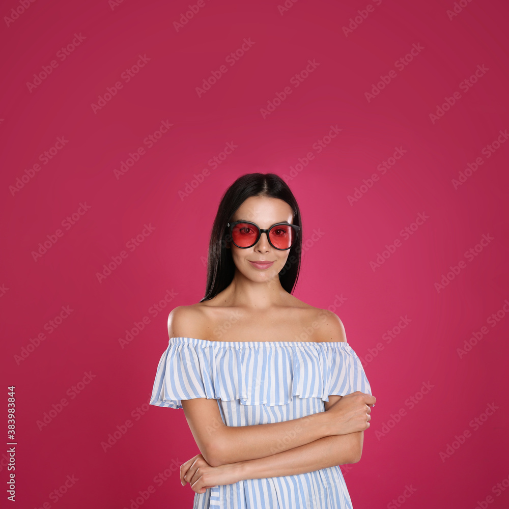 Beautiful woman wearing sunglasses on pink background