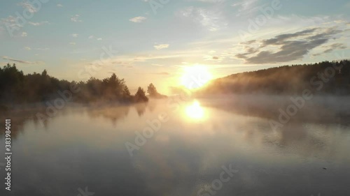 Flight on the drone over the river covered with mist in the early morning
