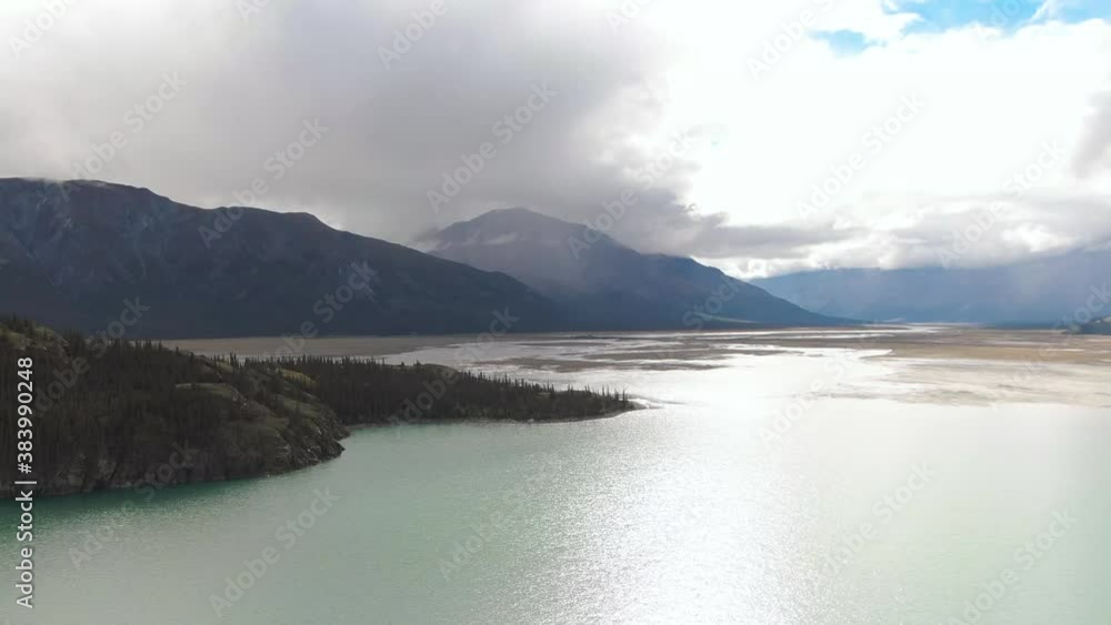 Gorgeous View of Scenic Island surrounded by Turquoise Lake and Mountains in Canadian Nature. Aerial Drone Shot. Yukon, Canada. Gorgeous View of Scenic Island surrounded by Turquoise Lake and Mountains in Canadian Nature. Aerial Drone Shot. Yukon, Canada.