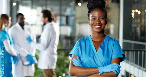 Canvas Print Portrait of African American happy beautiful woman physician in gloves smiling to camera in clinic