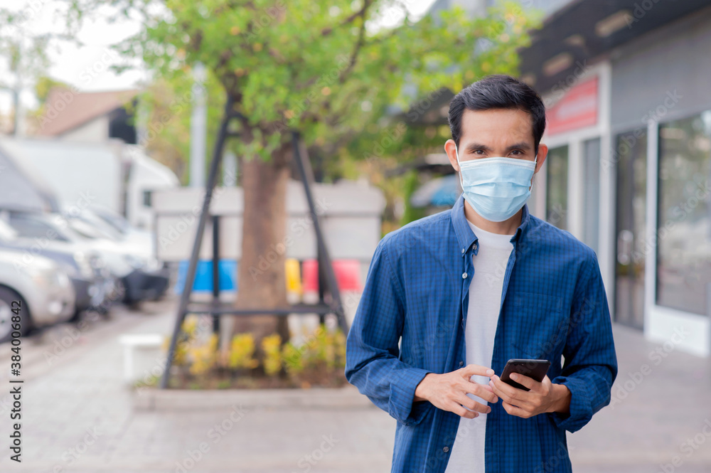 Asian man wear medical mask using cell phone walking on street Asian man wear medical mask using cell phone walking on street