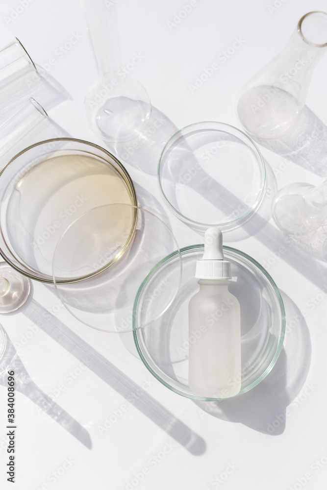 Top view of laboratory glassware and cosmetic glass bottle on grey background. Natural medicine, cosmetic research, bio science, organic skin care products. Top view of laboratory glassware and cosmetic glass bottle on grey background. Natural medicine, cosmetic research, bio science, organic skin care products.