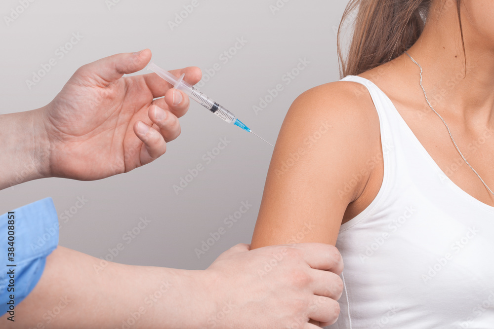 Doctor gives a syringe with vaccine to patient at clinic. Doctor gives a syringe with vaccine to patient at clinic.