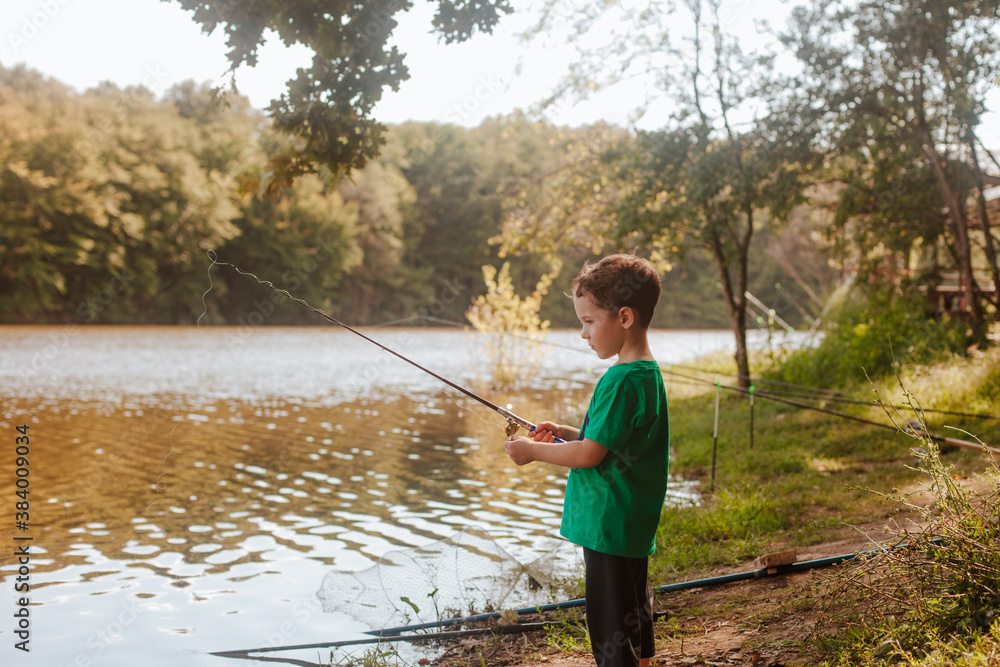 A small beautiful boy in a green t-shirt fishing on a fishing rod on the coast river. A small beautiful boy in a green t-shirt fishing on a fishing rod on the coast river.
