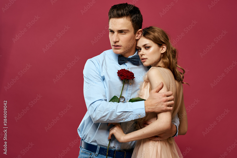 enamored man and woman with a red flower on a pink background hug each other Copy Space enamored man and woman with a red flower on a pink background hug each other Copy Space