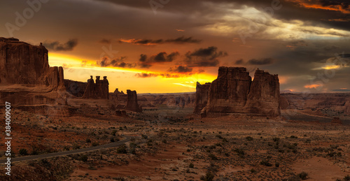 Panoramic landscape view of a Scenic road in the red rock canyons. Dramatic Colorful Sunset Sky Artistic Render. Taken in Arches National Park, located near Moab, Utah, United States.