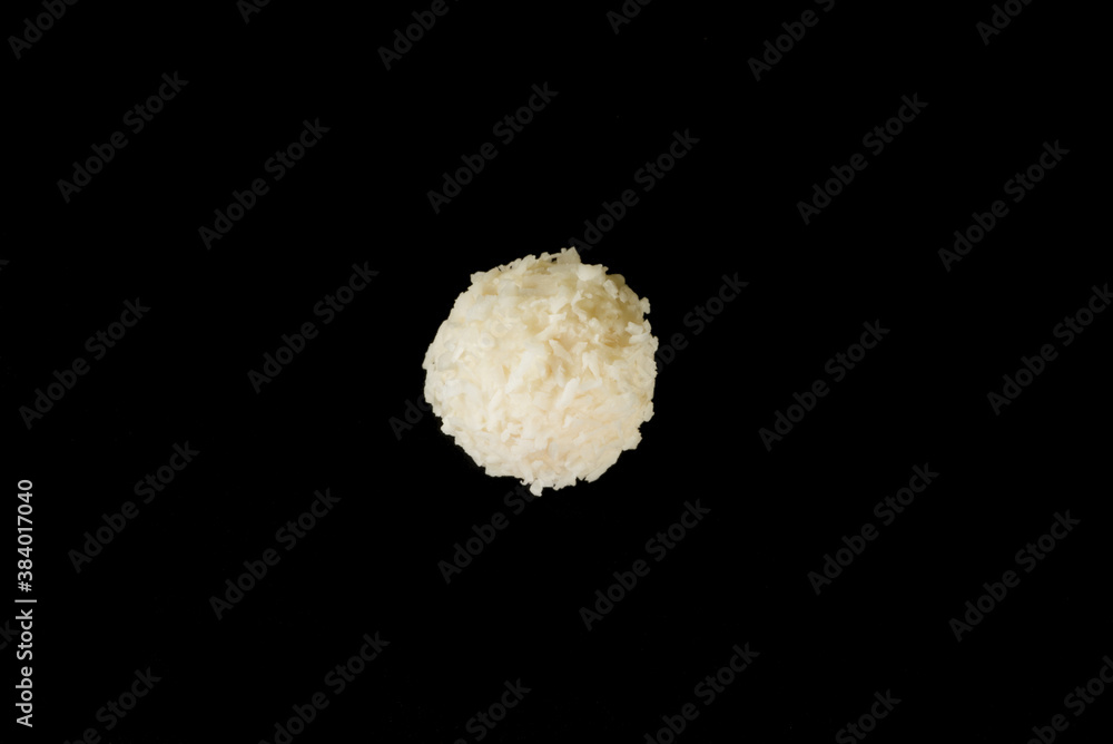Popular coconut sweets, round white candies in coconut flakes, isolated on a black background Popular coconut sweets, round white candies in coconut flakes, isolated on a black background