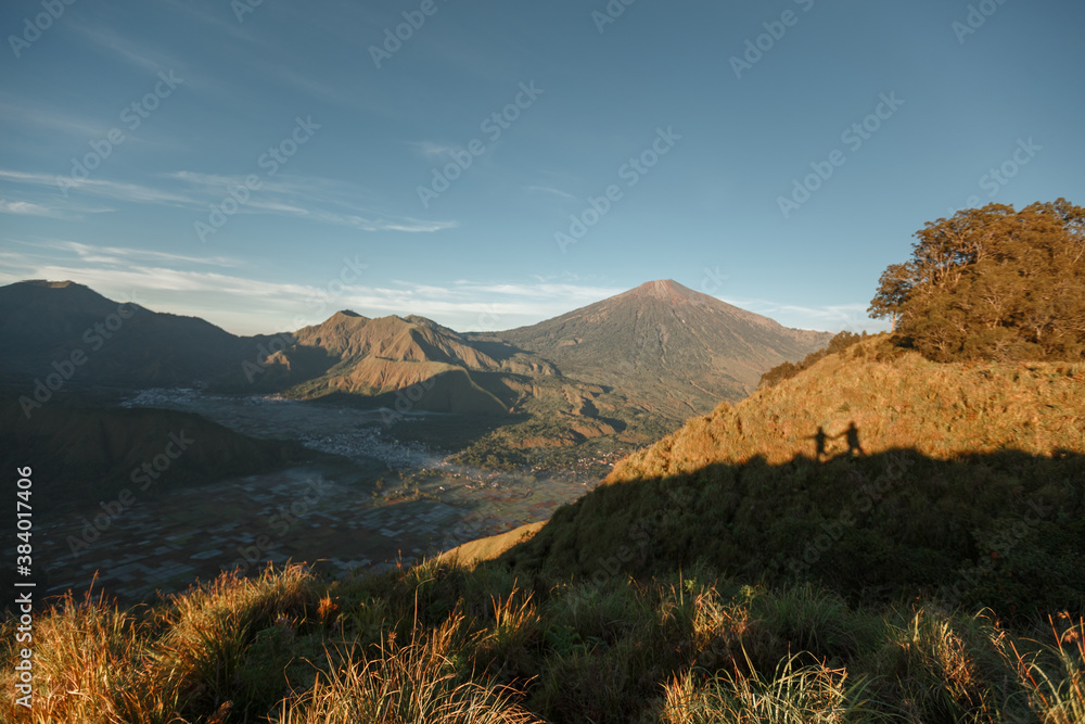 Obraz premium Landscape of Mount Rinjani from Sembalun Village, East Lombok. Couple silhouettes on the grass